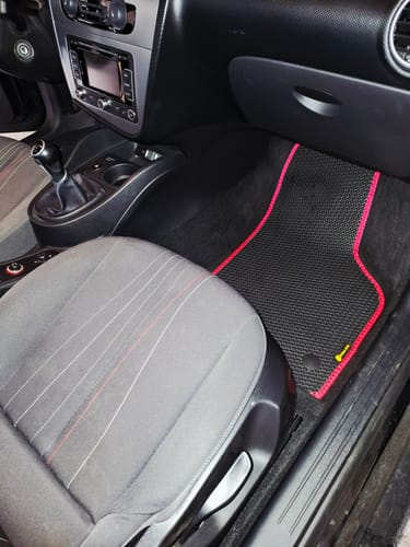 Zdjęcie od klienta przedstawiające dopasowany czarny dywanik samochodowy z czerwonym obszyciem, zamontowany w aucie.