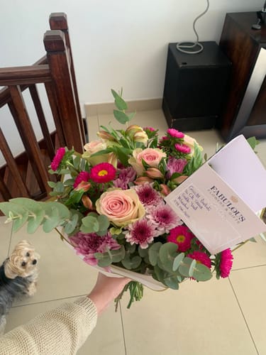 Customer holding their fresh One Of A Kind Bouquet, a vibrant arrangement of pink, purple, and cream flowers.