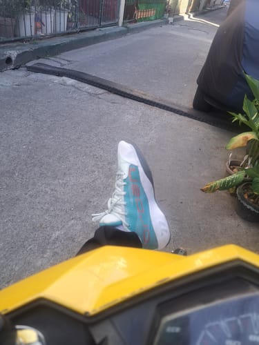 A customer's first-person view of their Nike Luka 77 'Love Letter' basketball shoe while sitting outdoors on a scooter.