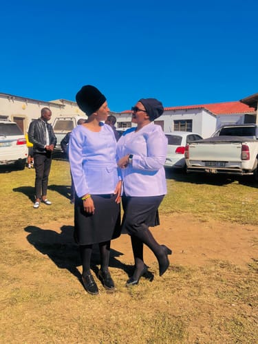 Reviewer wearing the black Miss Black Novi 1 Court heels outdoors with another person.