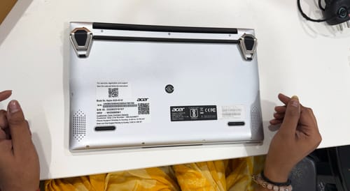 A reviewer shows the silver Casence AirStand for Laptop attached to the bottom of a silver laptop on a desk.