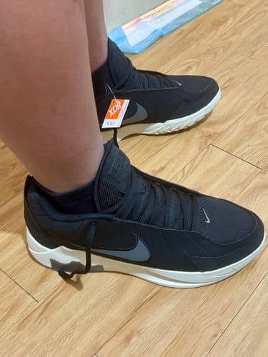 A customer wearing the black Nike Men's LeBron Witness IX EP Basketball Shoes with white soles indoors.