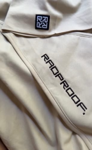 Close-up: Customer's soft beige Baby Blanket & Baby Beanie Bundle, showing the embroidered logo.