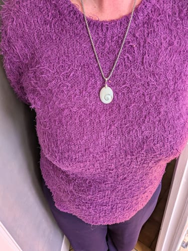 Cliente portant le pendentif Oeil de Sainte Lucie sur un pull violet.