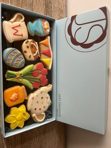 Customer's open Easter Breakfast Deluxe Biscuit Box showing nine colorful, hand-decorated biscuits in various breakfast shapes.