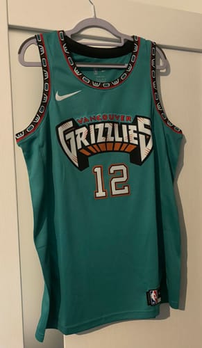 Un recensore mostra la parte anteriore della maglia NBA dei Memphis Grizzlies, in stile retrò Vancouver, appesa a una gruccia.