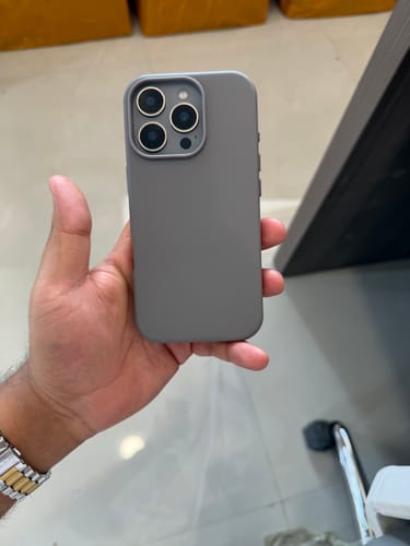 Customer's hand holding an iPhone with the sleek, graphite grey Signature Leather Magsafe Case.
