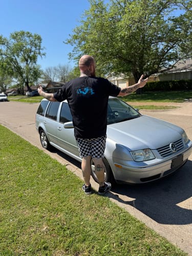 Customer seen from behind wearing the black 80Eighty® Limited Edition DCG87 Shirt outdoors by a car.