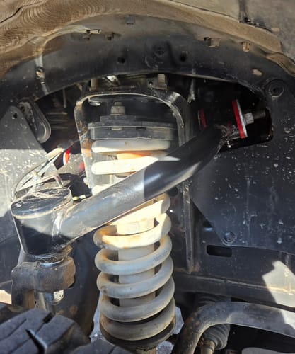 Customer's close-up view of the black Upper Control Arm installed in the wheel well of a Toyota Tacoma.