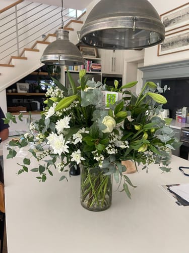 Customer's large White Purity Vase Arrangement with fresh white flowers and greenery on a kitchen island.