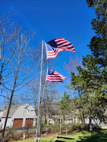 Customer's Betsy Ross Flag flying on a flagpole outdoors below a modern American flag on a sunny day.
