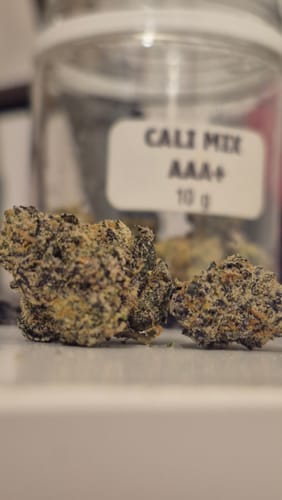 Customer's close-up of two dense CALI MIX AAA+ buds, with the product jar out of focus in the background.