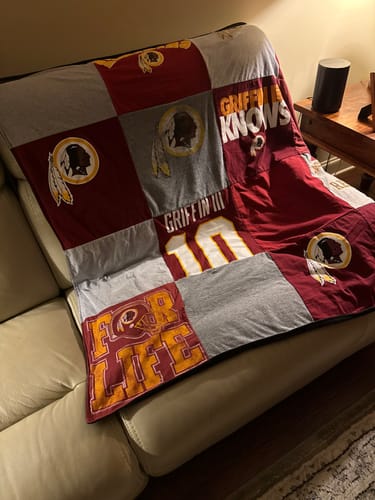 Customer's Project Repat T-Shirt Quilt made from Washington football t-shirts, draped over a sofa.