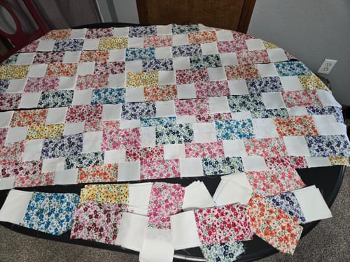 Reviewer's Brick Prairie Precut Quilt Kit being assembled. The colorful quilt top is partially sewn and laid out with extra pieces.