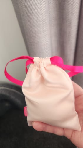 Customer holding the light pink satin storage pouch for their Lem Clitoral Massager.