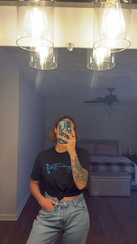 Reviewer in a mirror selfie wearing the black 80Eighty® DCG87 Shirt tied in a knot at the front.