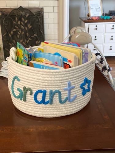 Customer's personalized knitted basket with the name 'Grant' in blue yarn and a star, filled with children's books.