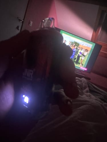 Partial view of a customer holding the JNR Falcon X Plus 28000 vape in a dark room, with the screen illuminated.