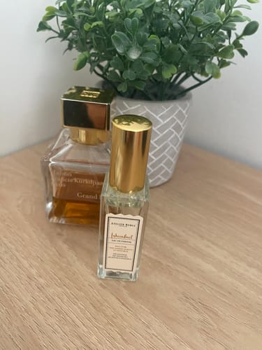 Customer's Istanbul Eau de Parfum bottle with a gold cap, sitting on a wooden surface next to a plant.