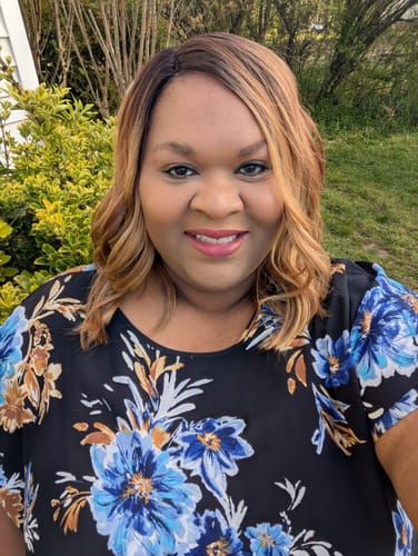 Reviewer smiling outdoors wearing the wavy, ombre Outre Every Wear HD Lace Front Wig with a side part.
