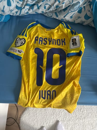 Un client montre le dos de son maillot d'Ukraine jaune, personnalisé avec le nom PASYNOK, le prénom IVAN et le numéro 10.