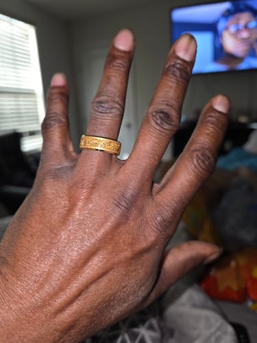 A customer's hand wearing the textured, gold Aureum ring.