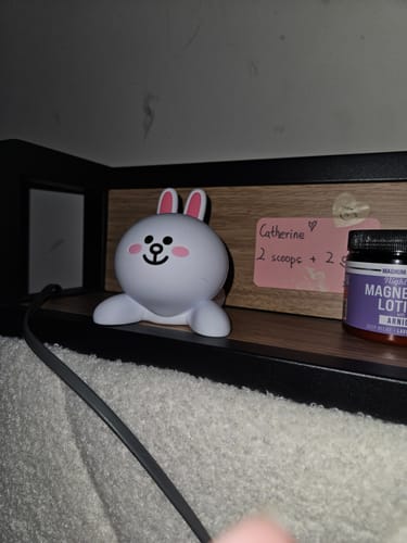 Customer's cute Cony character Brown & Friends Phone Stand resting on a wooden shelf.