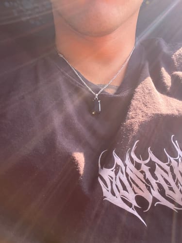 Primer plano de un cliente que lleva el colgante Void Onyx sobre una camiseta negra.