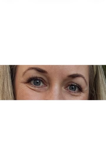 Kundin zeigt eine Nahaufnahme ihrer Augen mit langen Wimpernextensions, die mit DIY SUPER BOND CLEAR befestigt sind.