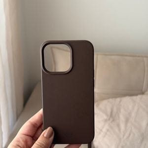 Cliente segurando uma capa de celular marrom, na cor Mocha Mousse, na mão.