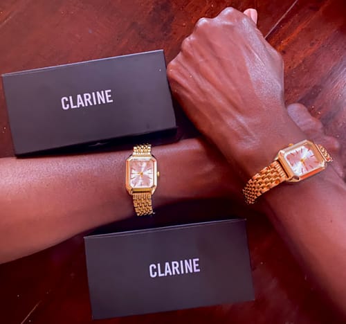 Reviewer shows two gold CLAIRE DE MAINS watches on two wrists, with the black product boxes.