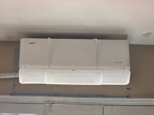 Un cliente muestra el deflector para aire acondicionado blanco instalado en una unidad interior.