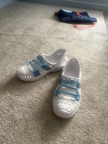 Customer's new Wildpool shoes in Skinny Dip on a carpet, with the branded carrying bag in the background.