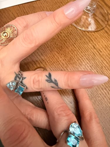 Reviewer showing two Navae Birthstone Rings with light blue stones, one on each hand.