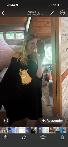 Cliente sorrindo em uma selfie no espelho, vestindo a Camisola Pandinha preta. A peça oversized tem uma estampa de capivara.