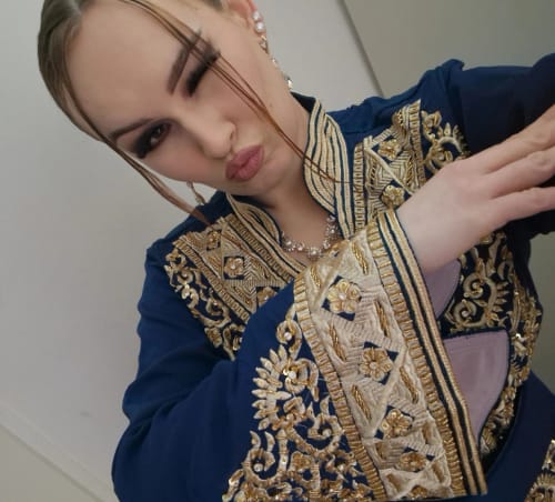Close-up of a reviewer wearing the blue Caftan Afsana, showing the detailed gold embroidery on the collar and sleeves.