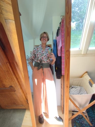 Cliente portant le Pantalon Suwannee abricot avec une blouse à fleurs.