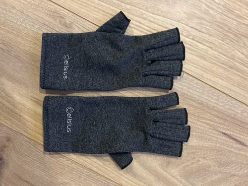 Photo d'un client : une paire de gants de mobilité Cellsius gris et sans doigts, posés à plat sur une surface en bois.