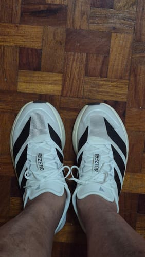 Reviewer's top-down view of the white adidas Adizero Boston 13 running shoes on their feet.