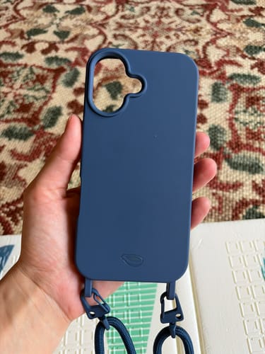Mão de um cliente segurando a Cordinha Nora azul, conectada a uma capa de celular da mesma cor.