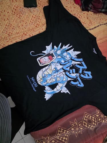 Un cliente muestra la camiseta negra Sea Rage 130 extendida, destacando el estampado de un dragón marino azul.