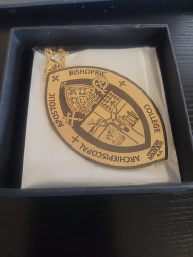 Reviewer's custom engraved pendant necklace with a detailed crest design, displayed in its gift box.