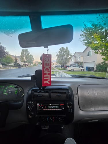 Reviewer's red 80Eighty Smoke Ice Air Freshener hanging from the rearview mirror inside a Ford Ranger.