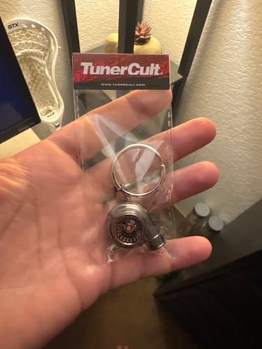 A person holding the Turbo Keychain in its original clear packaging in their hand.