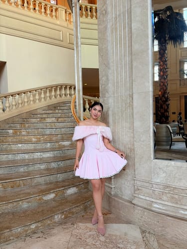 Reviewer wearing the pink Dolly Polka Dot Dress with the petticoat on a grand staircase.