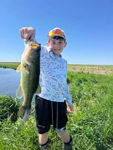 Customer showing a young person outdoors wearing the 'Cross Pattern' Youth Performance Shorts while holding a large fish.