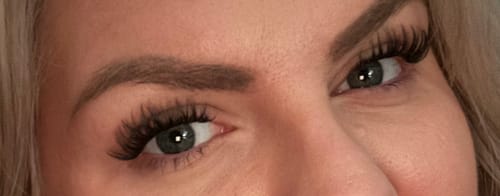Nahaufnahme der Augen einer Kundin, die lange und volle AYLASHES Wimpernverlängerungen trägt.
