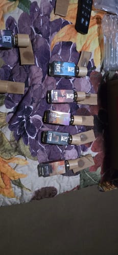 Customer's collection of small perfume bottles, including He Loves Sky Blue Capri!, on a floral comforter.