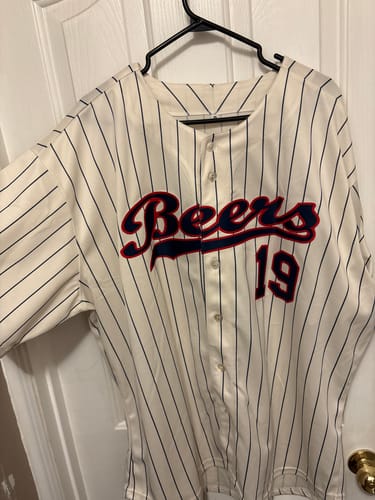 Customer's cream pinstripe baseball jersey with the custom name 'Beers' and number '19' stitched in navy and red.