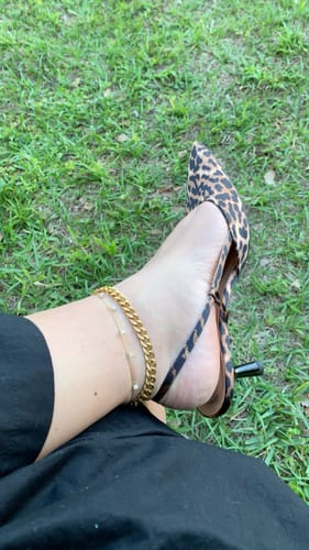 Customer's ankle showing the dainty Tide Anklet layered with a chunky gold anklet and leopard print heels.
